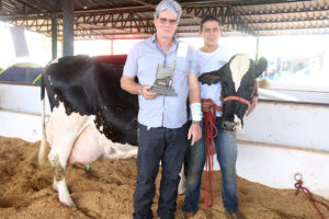 José Ronaldo Xavier Machado, com o troféu de campeão e o tratador com a Vaca Caçula, a mais produtiva do torneio